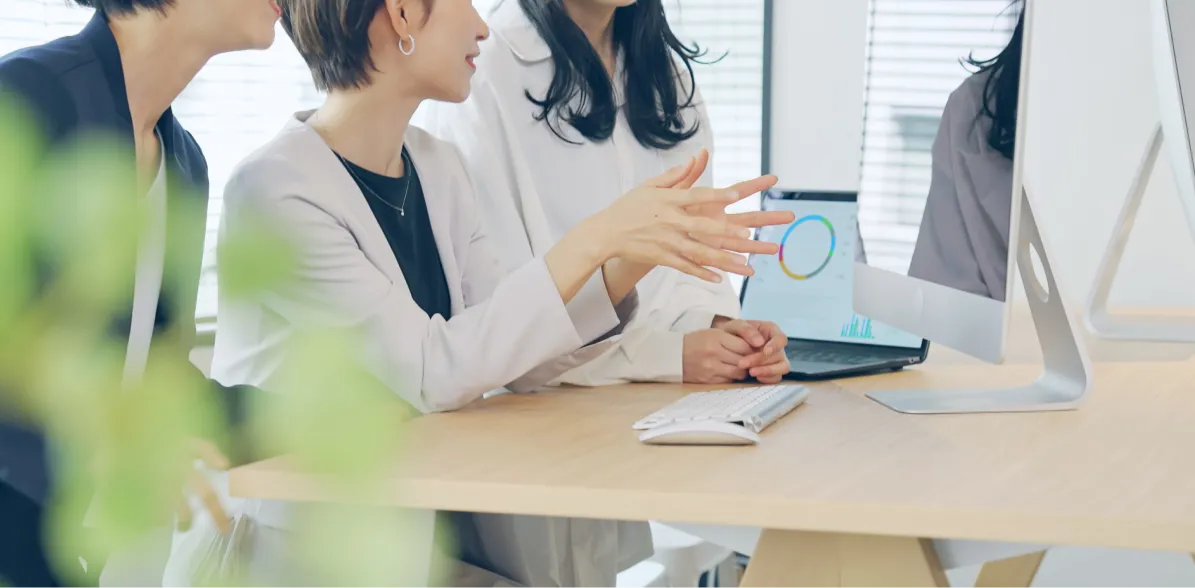 オフィスで資料を見ながら打ち合わせをする人たち